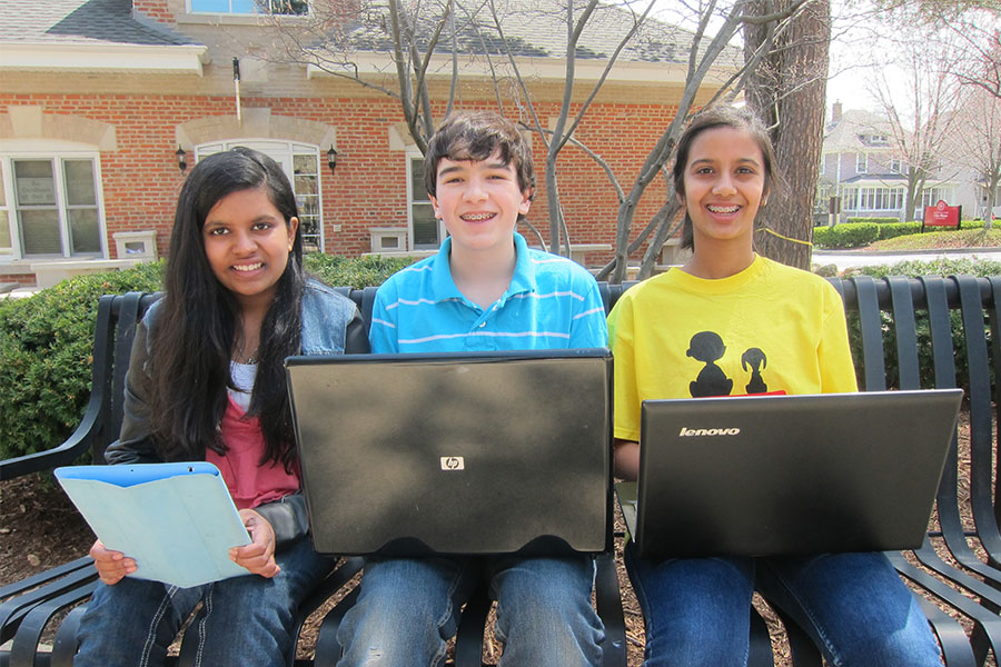 three high school students on laptops outside